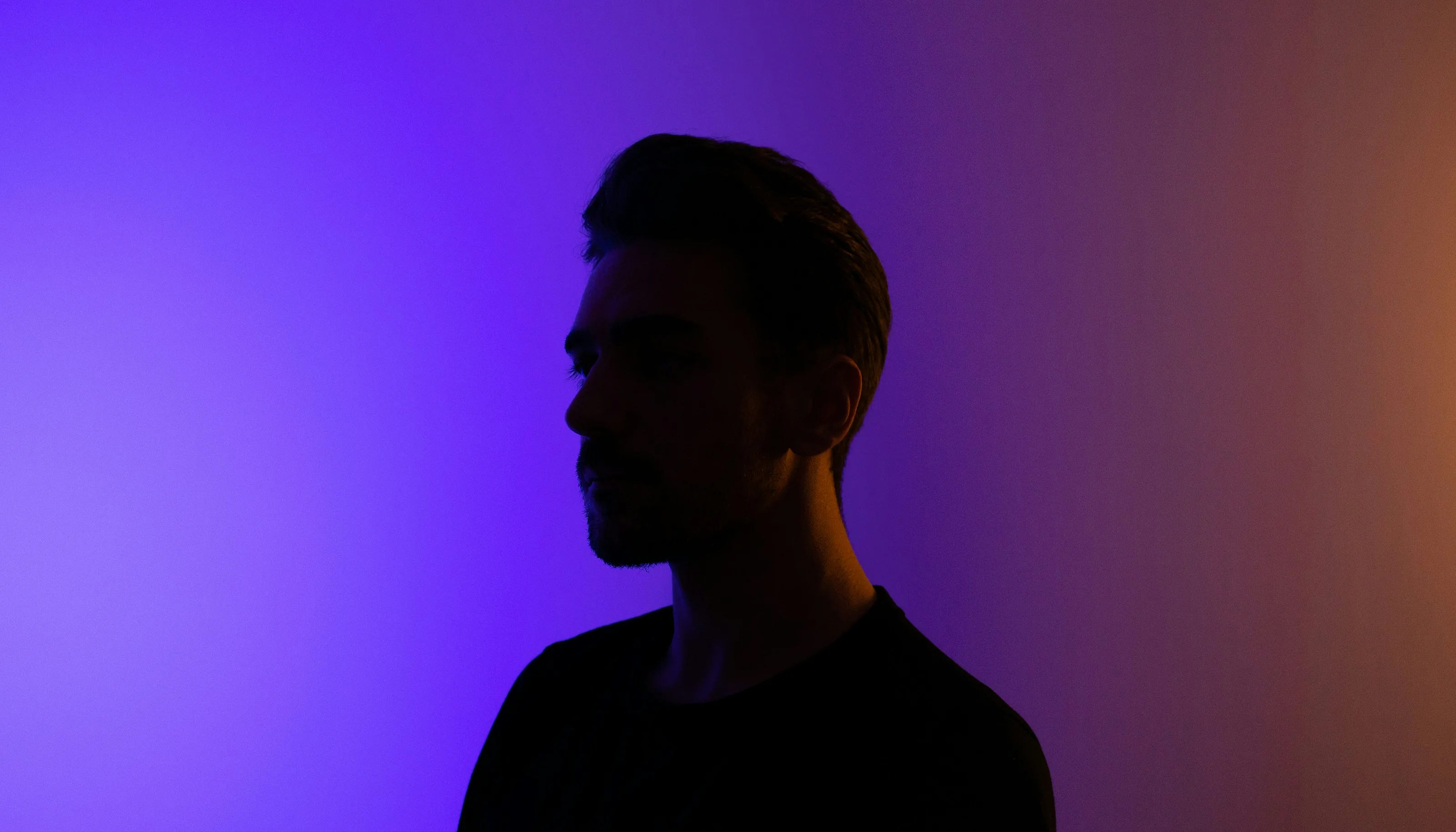 Man in profile against a violet-to-amber gradient